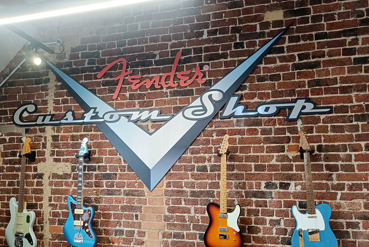 Backsteinwand mit Schriftzug Fender Custom Shop und vier Gitarren