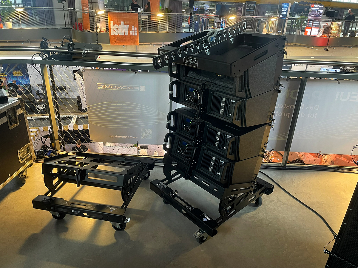 Rückansicht mehrerer übereinander angeordneter Pronomic XANA Topteile. Das oberste Topteil ist geöffnet, das Ampmodul demontiert. Links daneben: Dollywagen.
