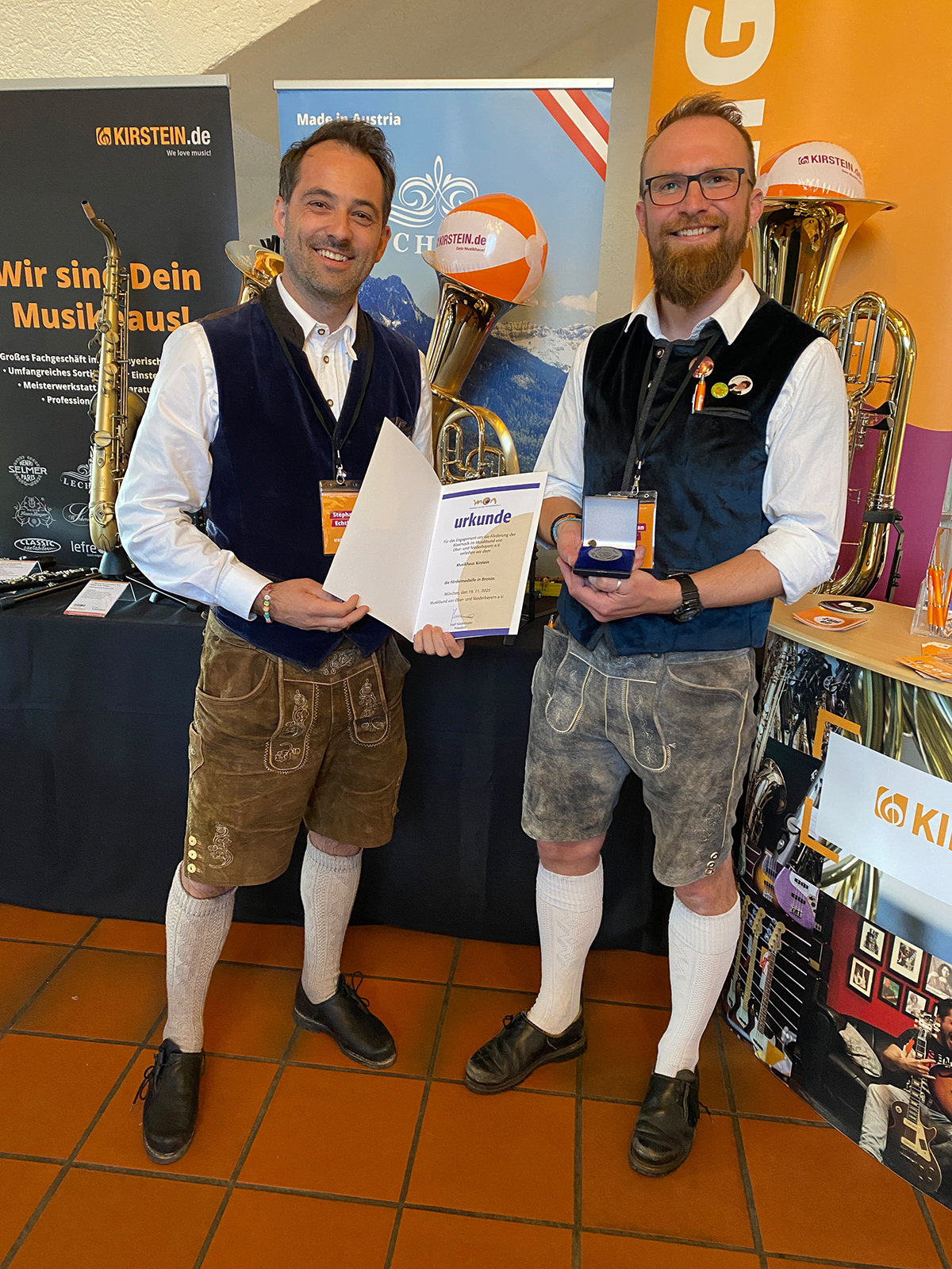 Stephan Echtler und Christian Mayr vom Musikhaus Kirstein mit der Urkunde und der Fördermedaille des MON