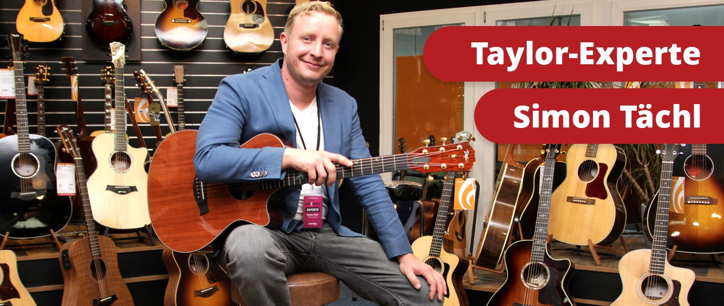 Taylor Guitars Experte Simon Tächl in der Gitarrenausstellung vom Musikhaus Kirstein zwischen vielen Westerngitarren