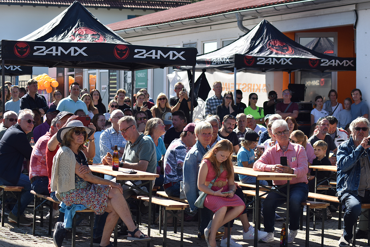 MusiConnect 2024: Publikum auf Bierbänken vor der Bühne im Außenbereich von Musikhaus Kirstein