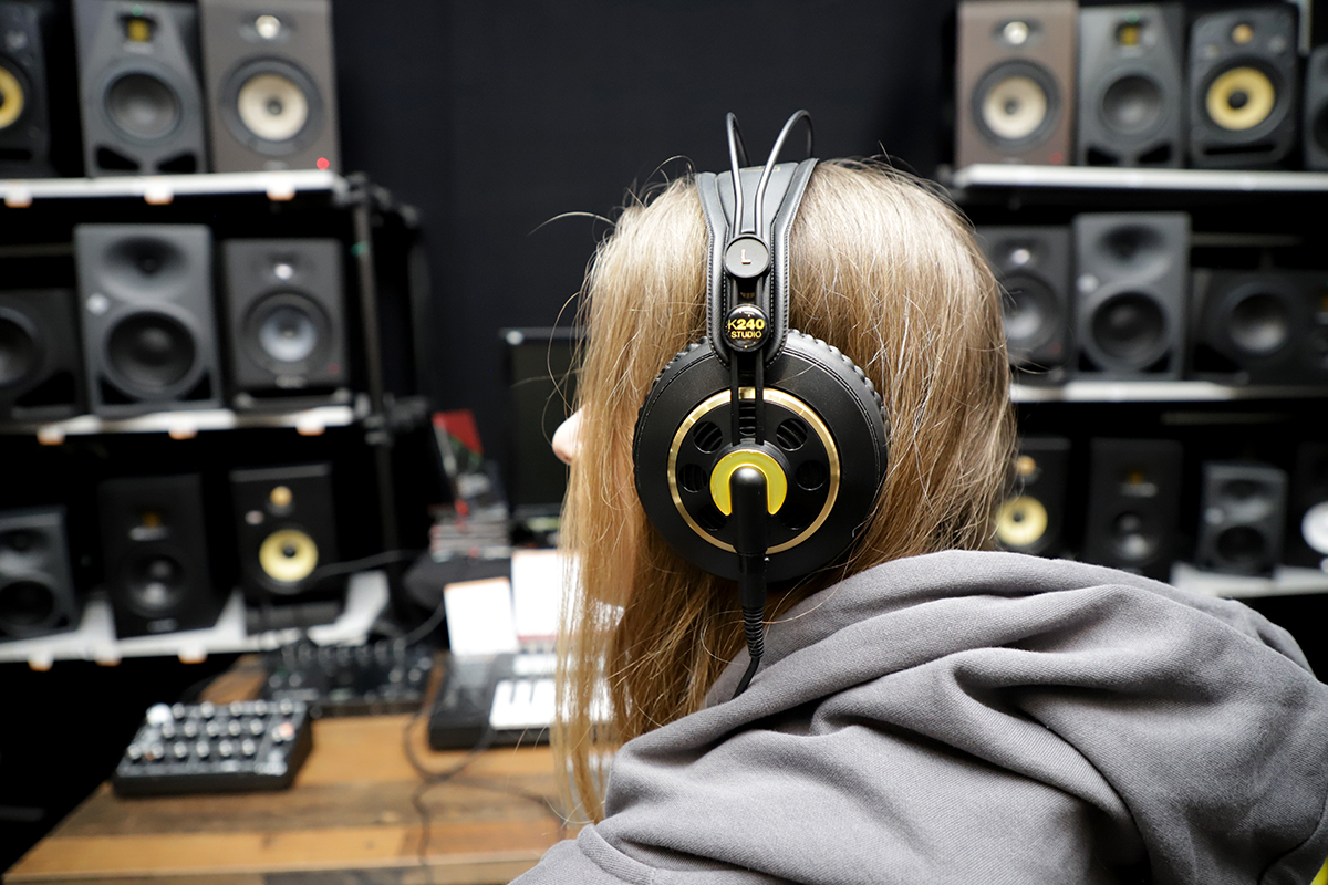 Person mit Kopfhörern vor Boxen im Musikhaus Kirstein